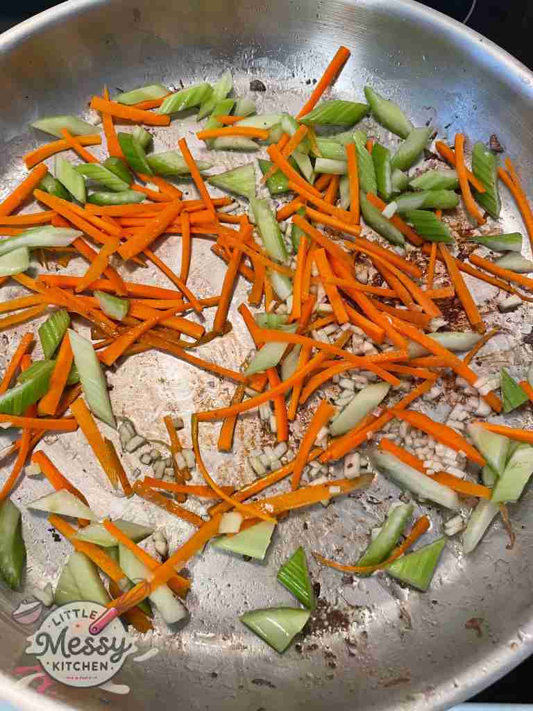 Garlic, carrots and celery sauteing in frying pan.
