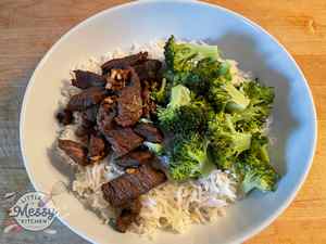 Serving of Asian Marinated Flank Steak served with steamed broccoli and rice in a white bowl.