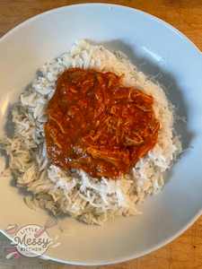 Chicken Tikka Masala on a bed of rice served in a white bowl. 