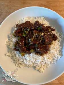 Serving of Mongolian beef on a bed of rice in a white bowl.