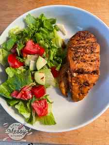 Asado Chicken breast served with a side of salad in white bowl.