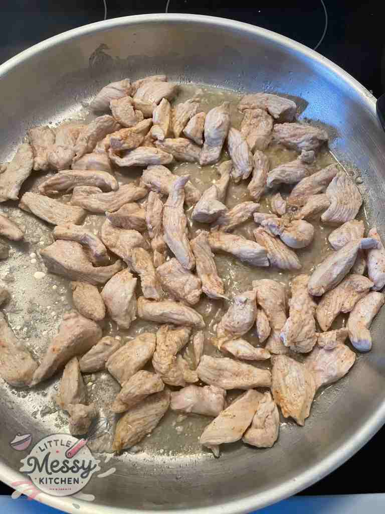 Chicken strips cooking in a skillet.