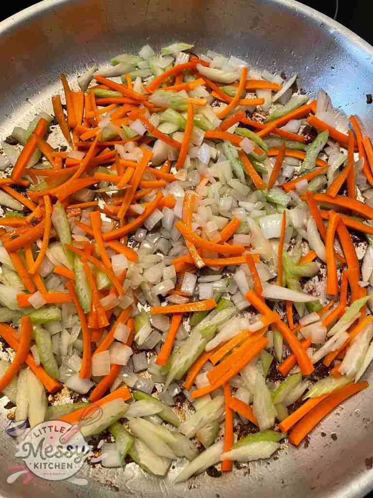 Onions carrots and celery in a frying pan.