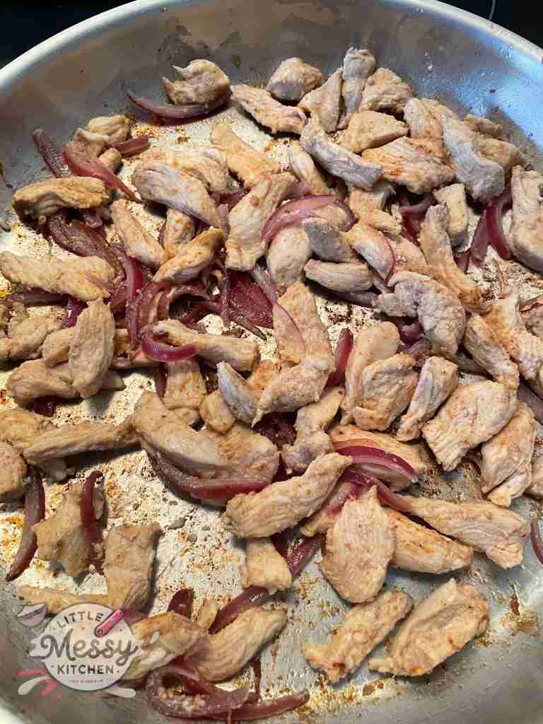 Chicken and onion cooking in a skillet.