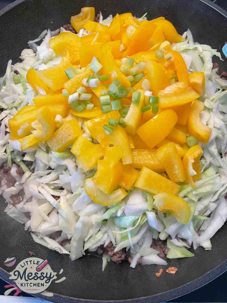 Cabbage and bell pepper added to the frying pan.