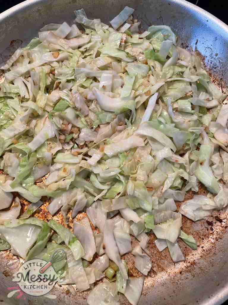 Cabbage added to the frying pan.