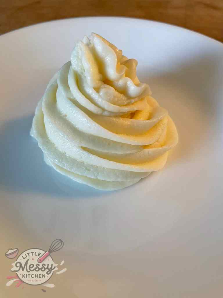 Buttercream frosting piped on a white plate.