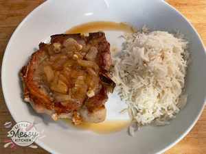 Tender pork chop served with a side of rice in a white bowl.