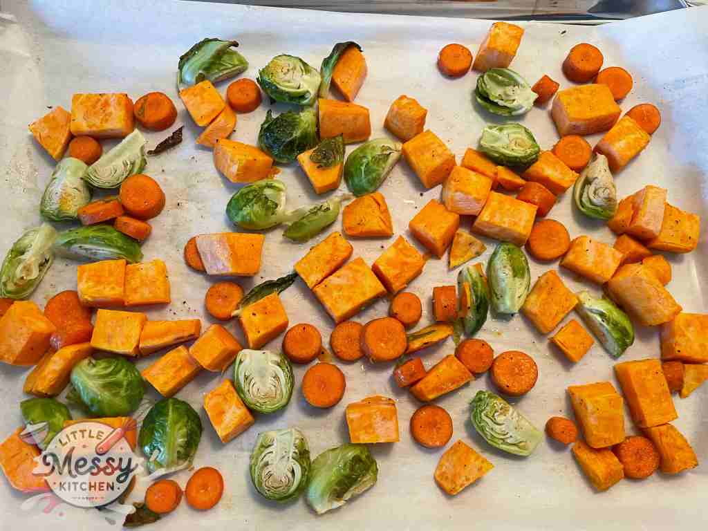 Sweet potato, carrots, and Brussels sprouts on a large sheet pan.