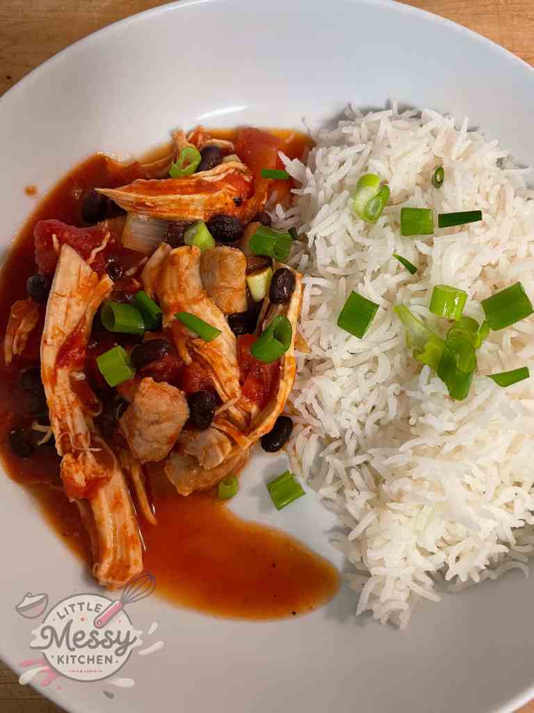 Serving of Creole chicken and Sausage served with rice in white bowl.