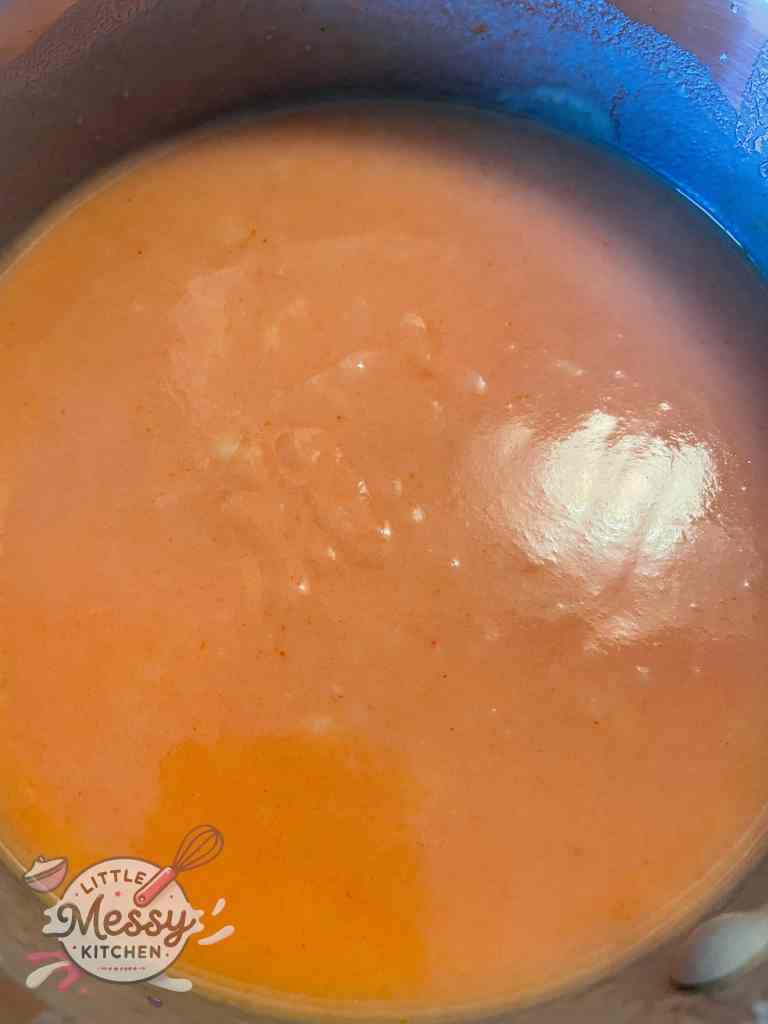 Chicken broth and tomato paste in saucepan.