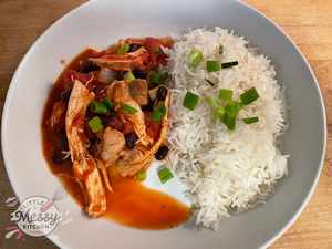 Serving of Creole chicken and Sausage served with rice in white bowl.