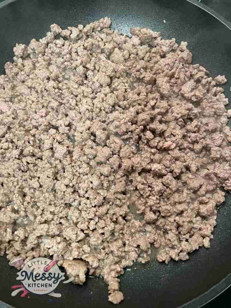 Ground beef cooking in a skillet.