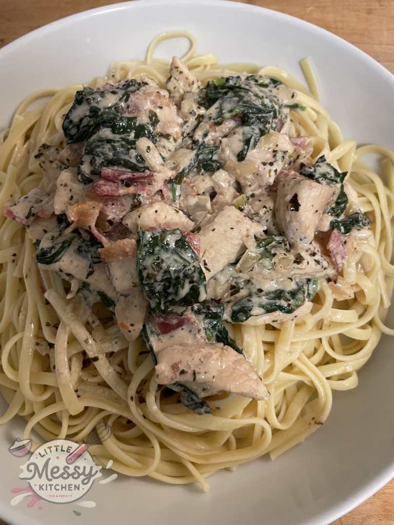 Chicken carbonara served on Linguine in a white bowl.