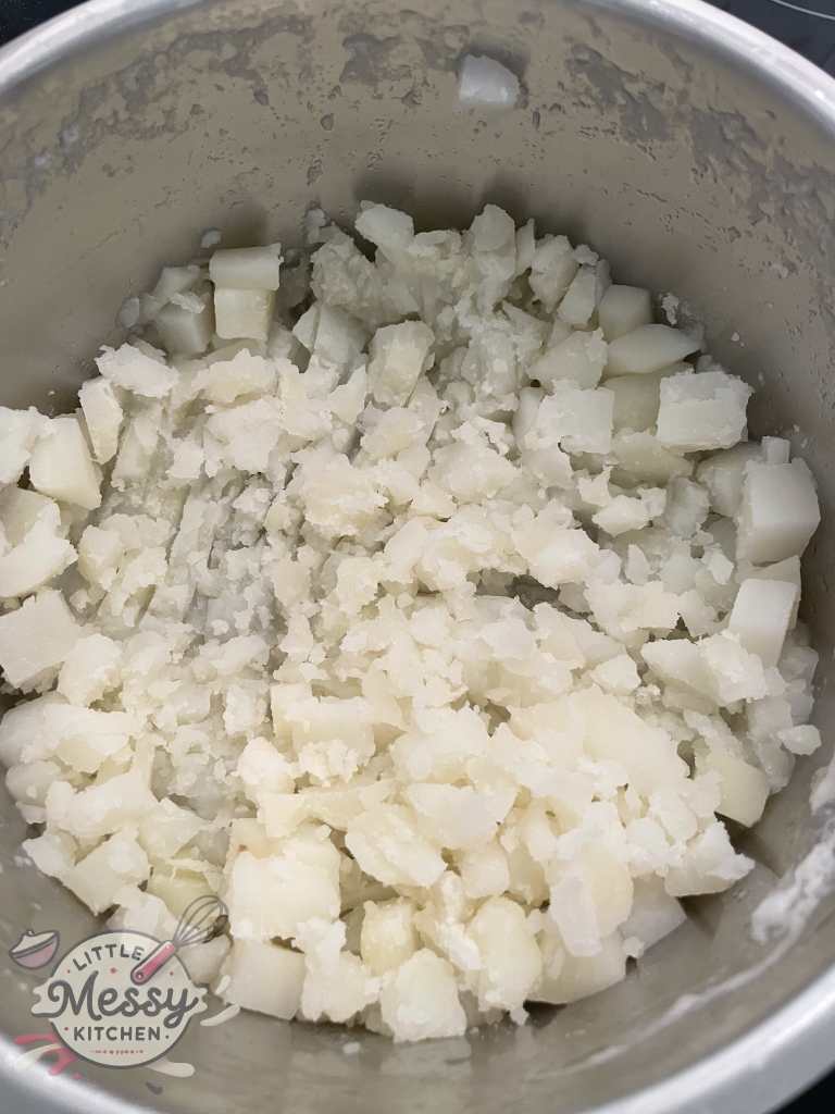 Potatoes roughly mashed in stockpot.