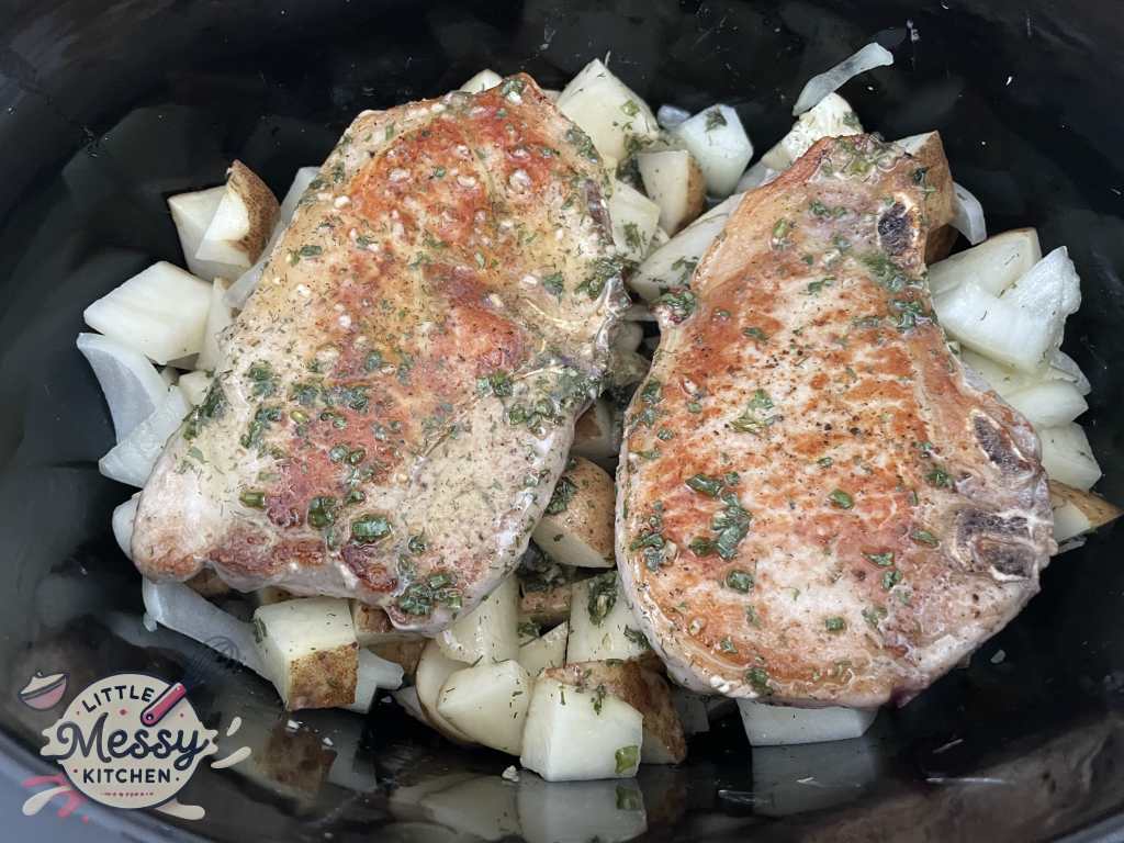 Seared Pork chops on potatoes in slow cooker.