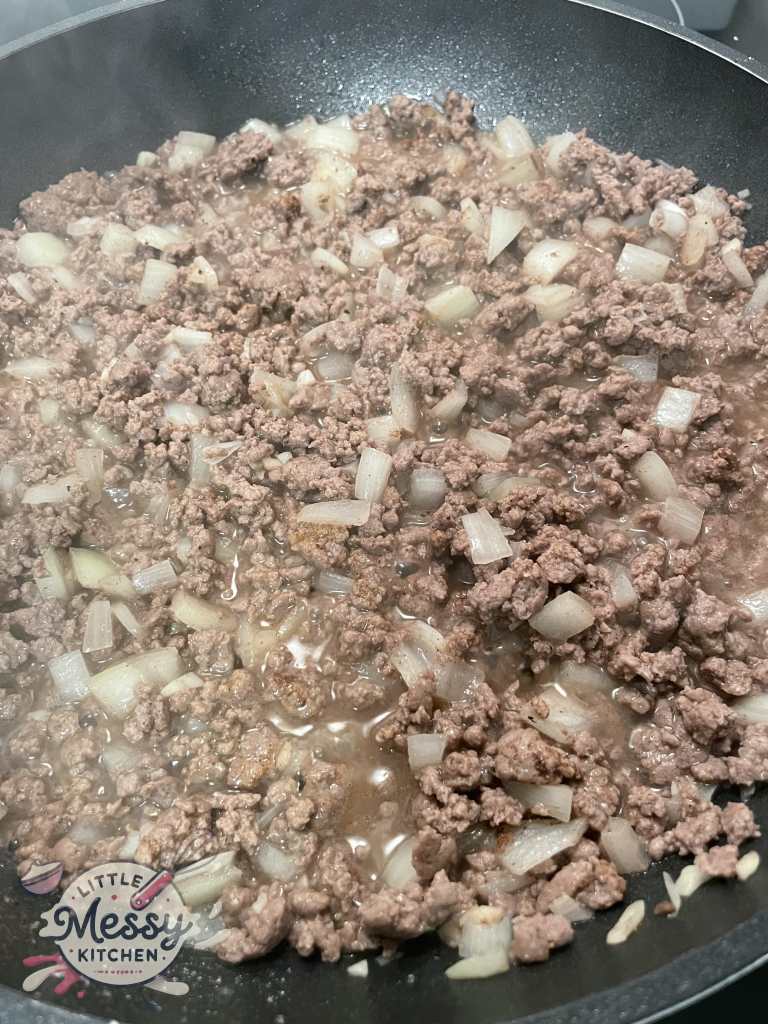 Spices and water added to meat in skillet.