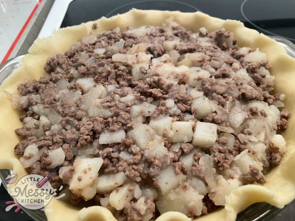 Tourtiere filing poured in prepared pie crust.