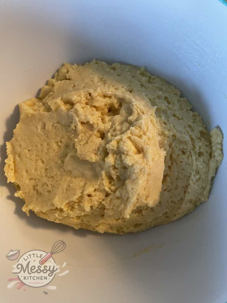 Cornmeal, flour, sugar, baking powder, and salt added to the wet ingredients in a mixing bowl.