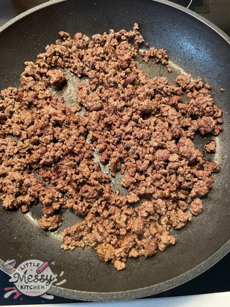 Ground beef cooking in skillet.